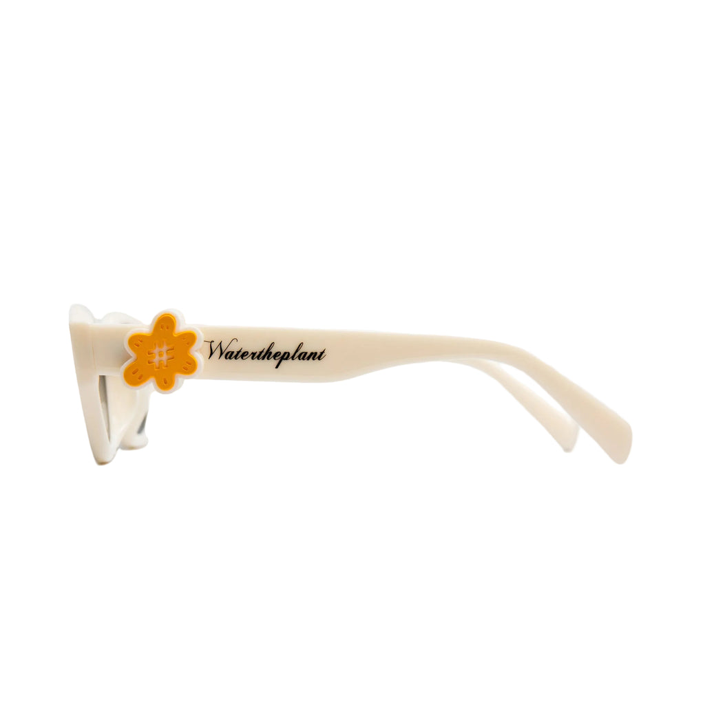 Off-white sunglasses with a bright orange flower accent on the temple arm, featuring the text 'Watertheplant' printed in black script.