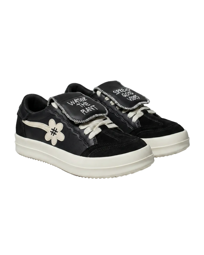 Black sneakers with white 'WATER THE PLANT' on the right and 'SPREAD GOOD VIBES' on the left text and a flower design on a white background