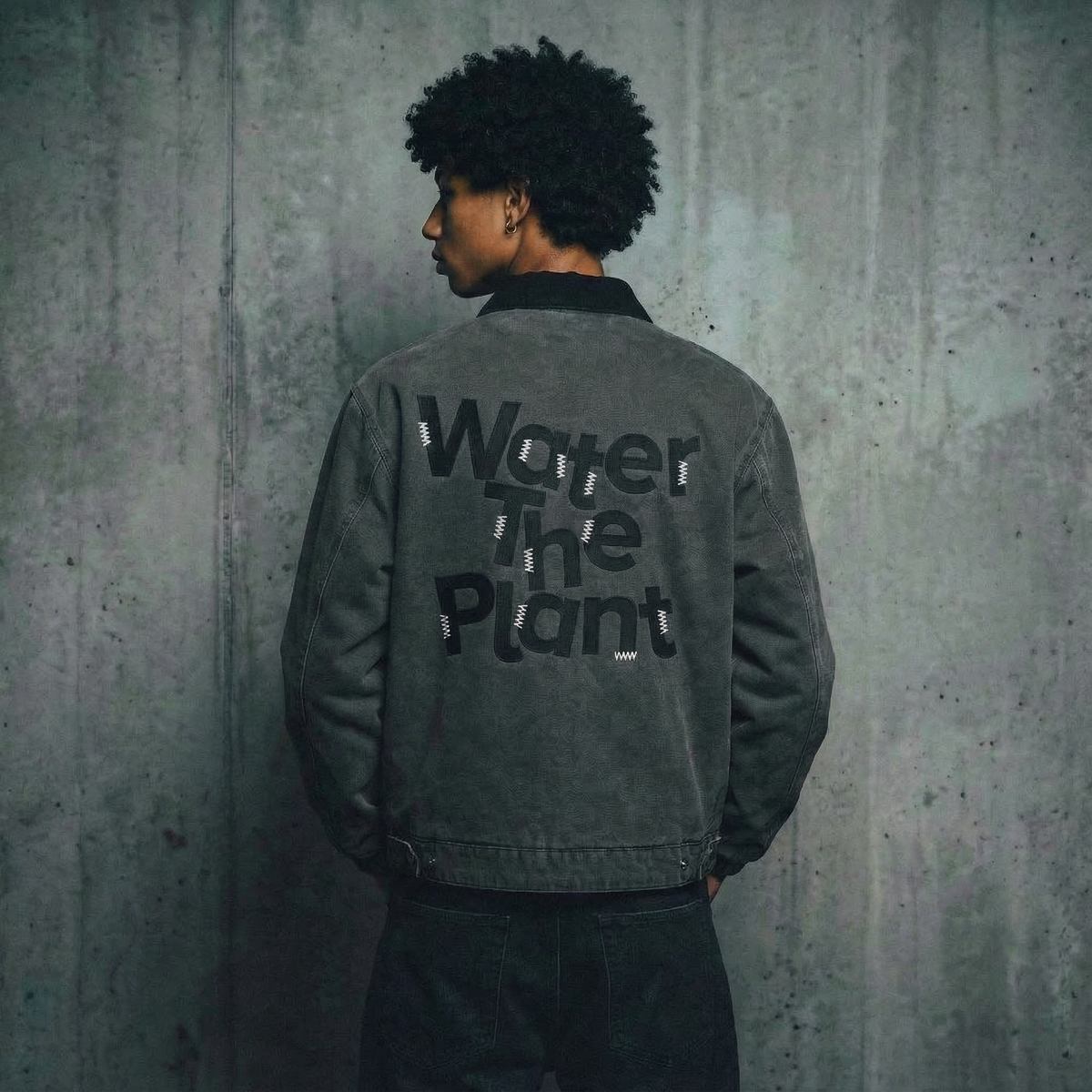 Person wearing a jacket with 'Water the Plant' text against a textured wall.