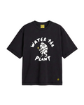 A black short-sleeve t-shirt with a white graphic print on the front reading 'WATER THE PLANT' around a cartoon monkey 'Koko', shown against a plain white background.