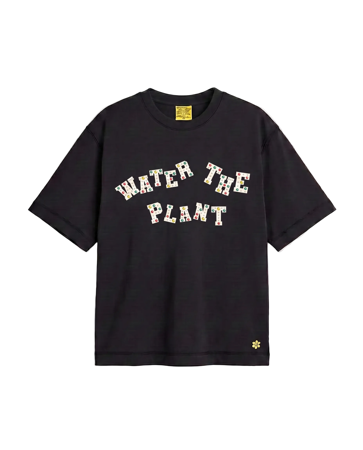 A black short-sleeve t-shirt with 'WATER THE PLANT' charms across the chest, featuring a small yellow flower logo on the bottom right hem and a yellow brand label inside the collar.