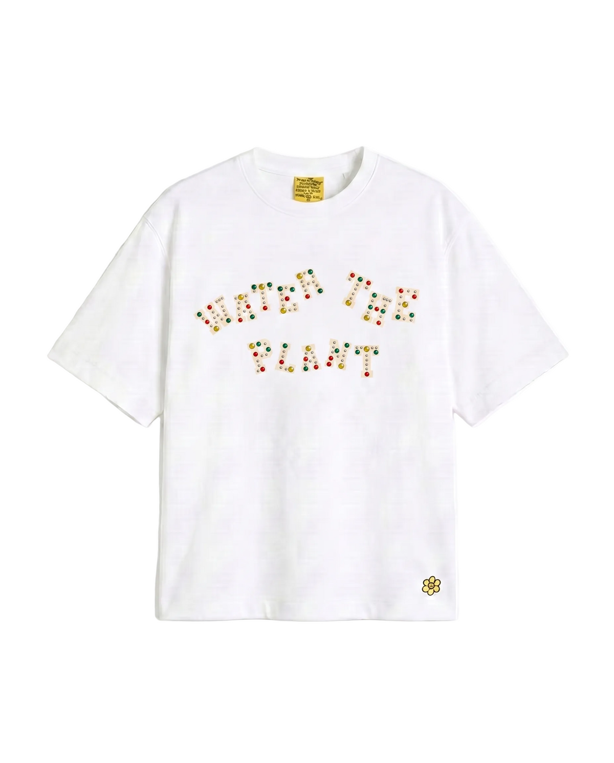 A white short-sleeve crewneck t-shirt featuring the phrase 'WATER THE PLANT' spelled out in colorful charms across the chest, with a Water The Plant flower logo on the lower left hem.