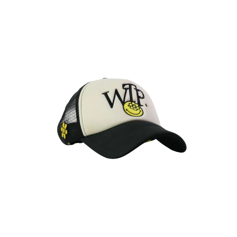 A trucker-style baseball cap with a cream-colored front panel, black mesh back, and black curved brim. The front panel features the embroidered black text 'WTP' with a yellow smiley face graphic inside the letter P, and small yellow flower details on the side mesh.