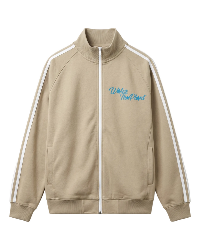 A beige zip-up track jacket featuring white stripes down the sleeves and a blue 'WATER THE PLANT' graphic on the left chest, displayed on a clean white background.