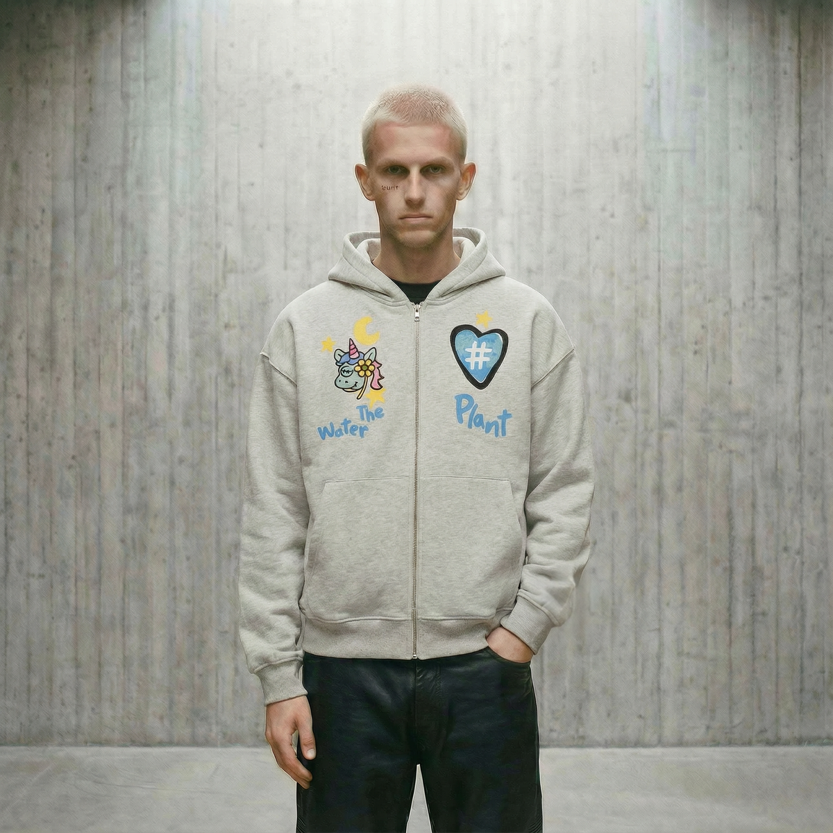 Person wearing a light gray hoodie with colorful graphics and text against a wooden paneled wall.