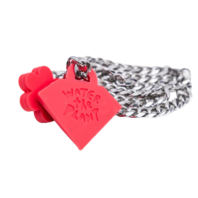 A silver-toned metal curb chain bracelet featuring a bright red silicone heart-shaped charm engraved with 'WATER THE PLANT' and a small red flower accent, shown on a plain white background.